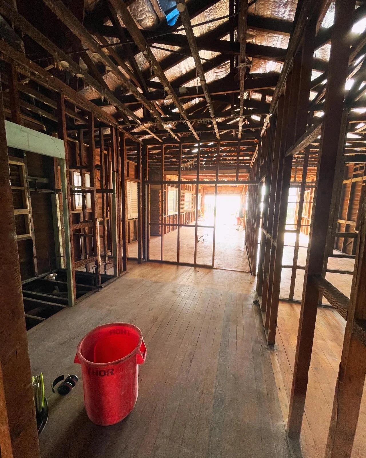 Same residential hallway after wall and ceiling linings were removed to expose timber framing